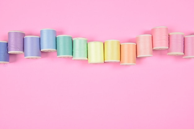 Zbliżenie na nici i igły w pastelowych kolorach